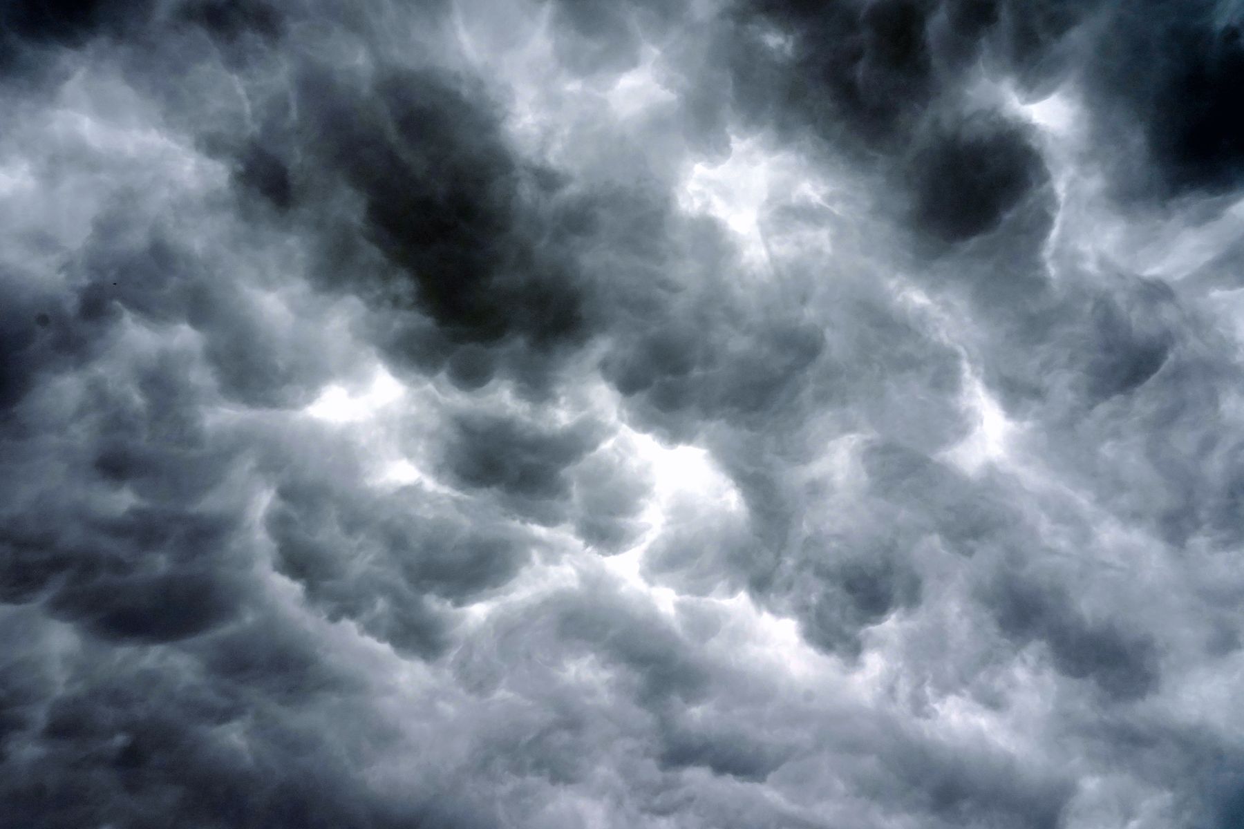 A sky filled edge to edge with dark, heavily textured storm cloud, with bright breaks showing between the darker cells.