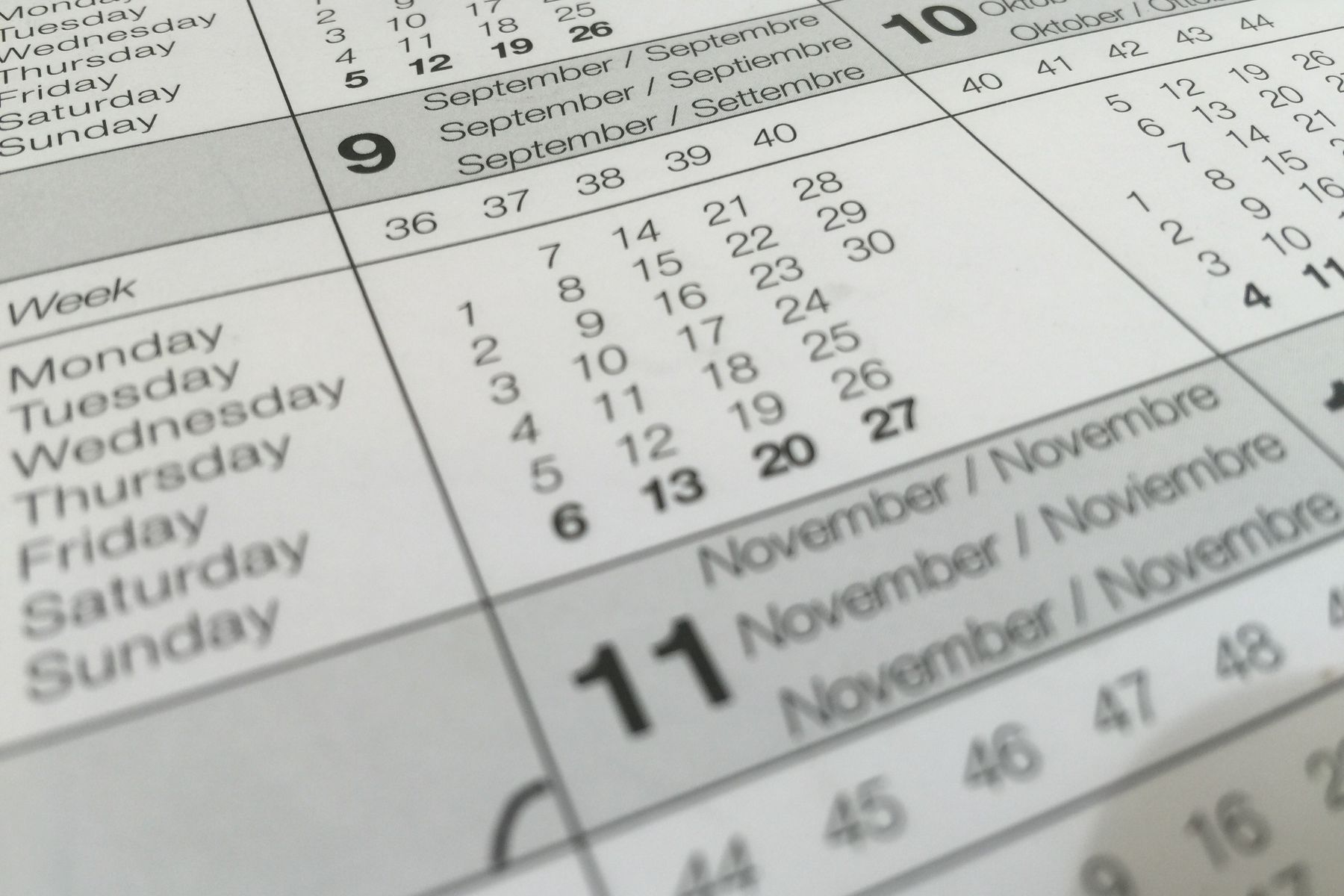 A close view of overlapping printed calendar pages showing week numbers, weekday names and month headings.